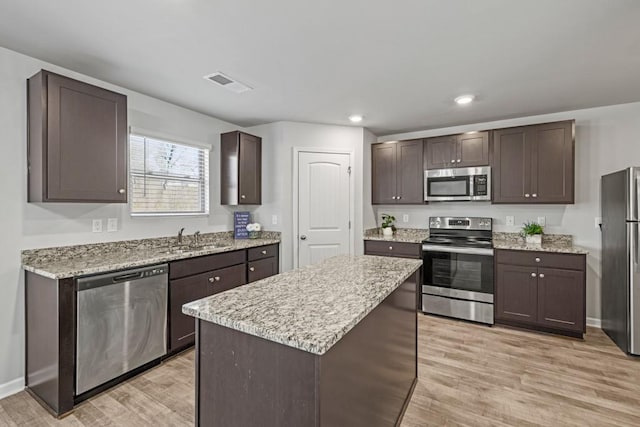 kitchen featuring sink, stainless steel appliances, a center island, dark brown cabinetry, and light hardwood / wood-style floors