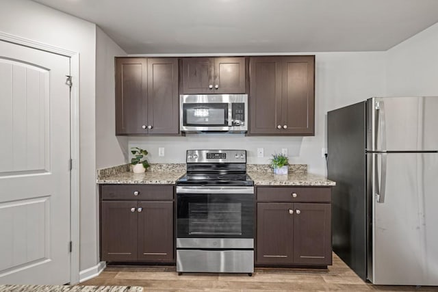 kitchen with appliances with stainless steel finishes, dark brown cabinets, and light hardwood / wood-style flooring