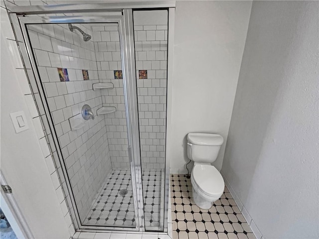 bathroom featuring toilet and a shower with shower door