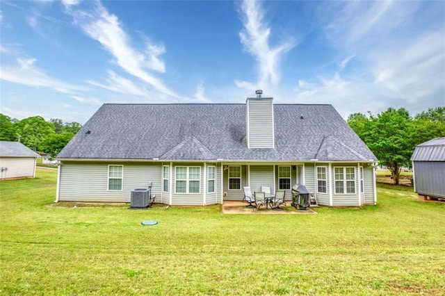 rear view of house with a chimney, central air condition unit, a yard, and a patio area