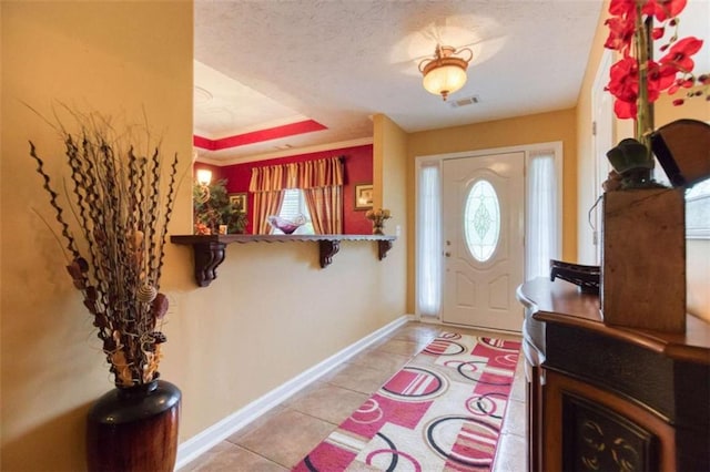 foyer with a textured ceiling, visible vents, a tray ceiling, baseboards, and light tile patterned flooring