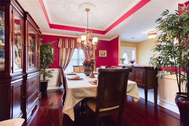 dining area with dark wood finished floors, a chandelier, a raised ceiling, and a healthy amount of sunlight