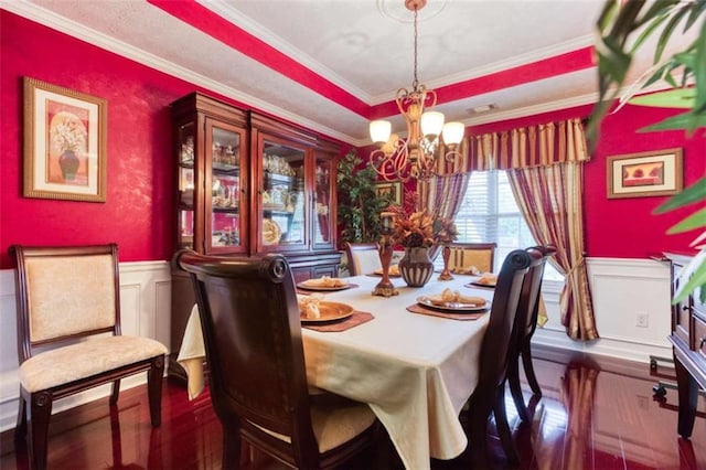 dining space featuring wainscoting, an inviting chandelier, crown molding, and a decorative wall