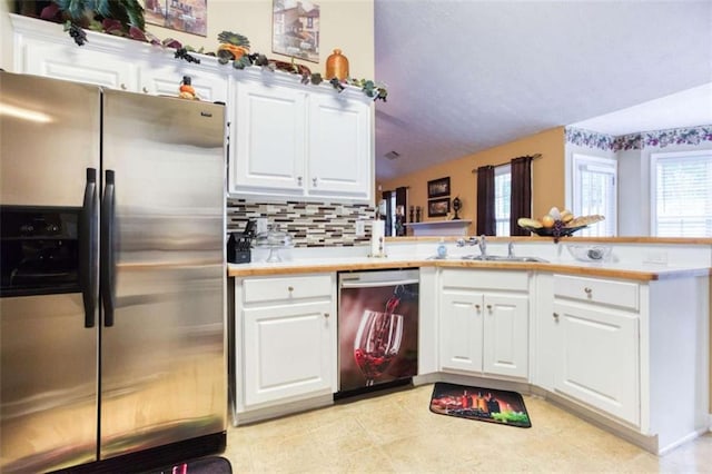 kitchen with decorative backsplash, stainless steel appliances, light countertops, white cabinets, and a peninsula