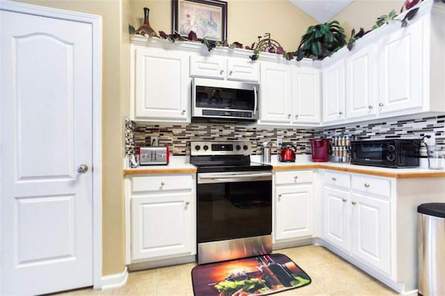 kitchen featuring decorative backsplash, stainless steel appliances, vaulted ceiling, white cabinetry, and light countertops