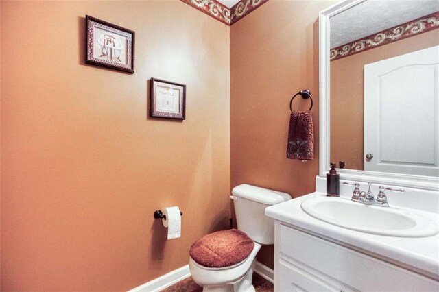 bathroom with toilet, vanity, and baseboards