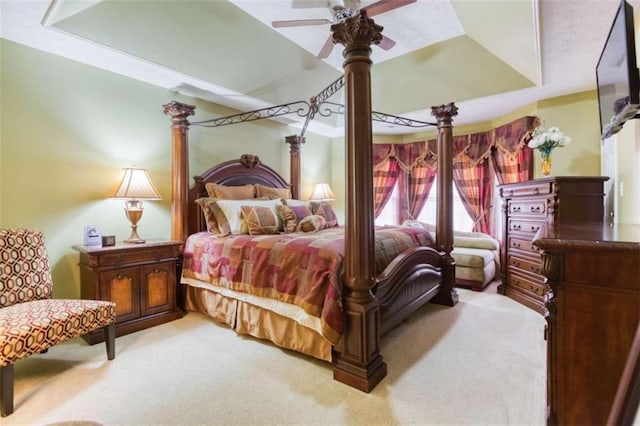 bedroom with a ceiling fan, light colored carpet, and a tray ceiling