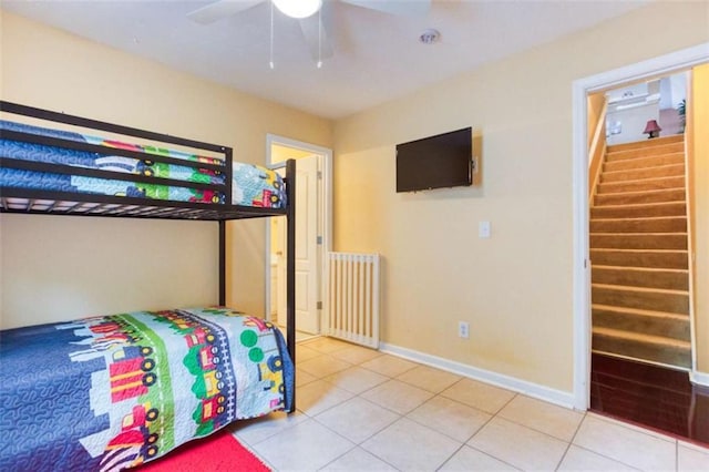 bedroom featuring light tile patterned floors, a ceiling fan, baseboards, and radiator
