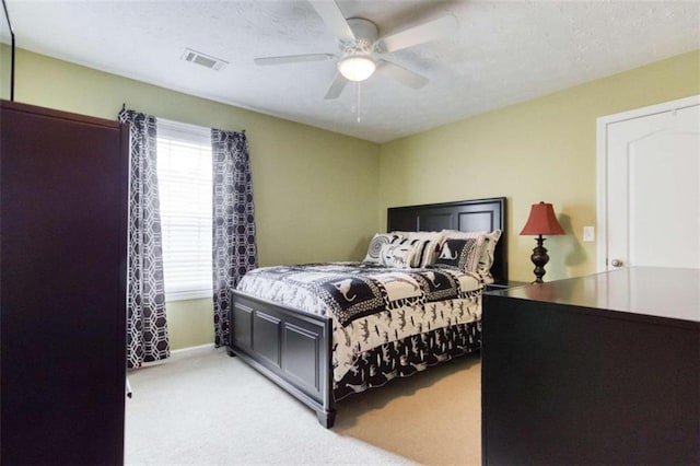 bedroom with visible vents, baseboards, a ceiling fan, and light carpet
