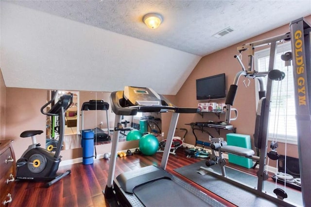 workout area featuring a textured ceiling, wood finished floors, a wealth of natural light, and visible vents