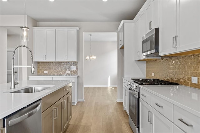 kitchen with a sink, baseboards, light countertops, and appliances with stainless steel finishes