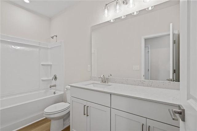 bathroom featuring toilet, wood finished floors, vanity, and shower / bathtub combination
