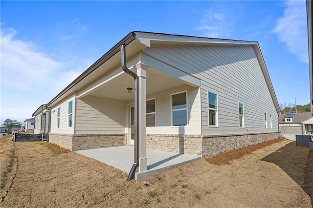 view of side of property with central AC unit, a patio area, and brick siding
