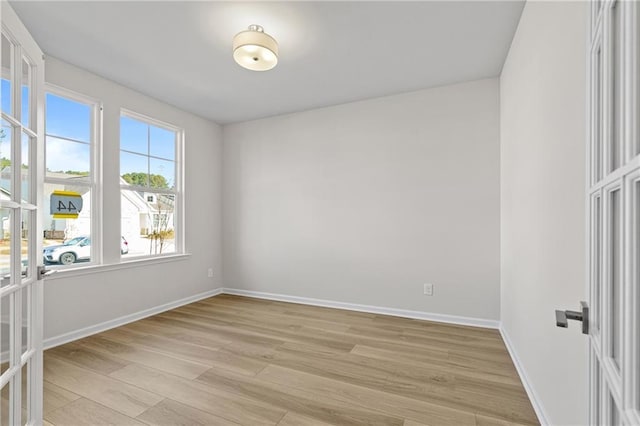 unfurnished room with baseboards and light wood-type flooring