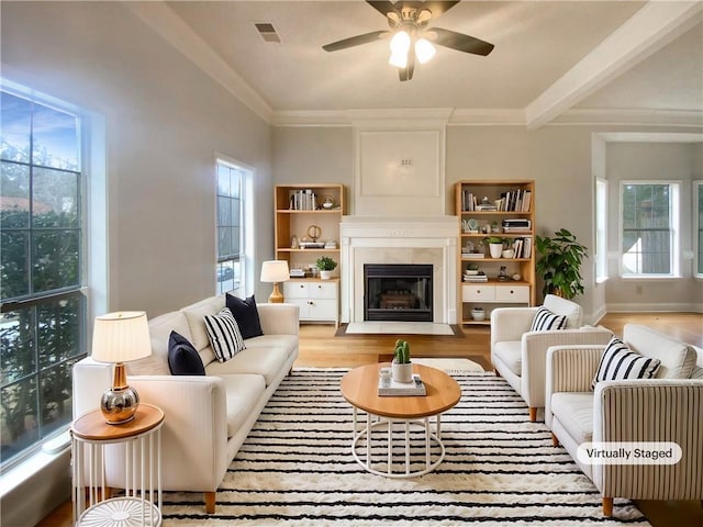 living room with beam ceiling, ornamental molding, light hardwood / wood-style floors, and ceiling fan