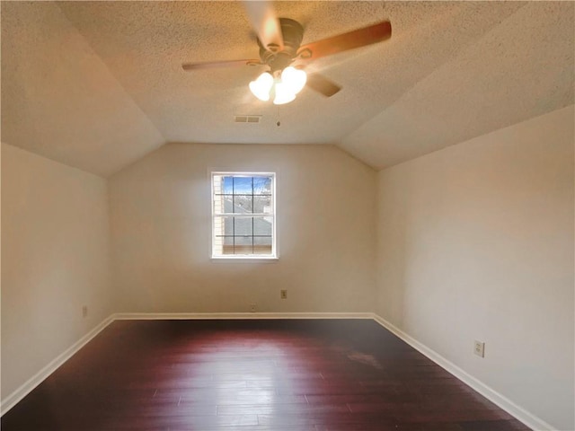 additional living space featuring ceiling fan, vaulted ceiling, dark hardwood / wood-style floors, and a textured ceiling