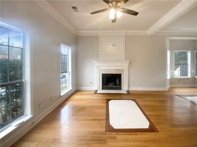 unfurnished living room featuring ornamental molding, a fireplace, light hardwood / wood-style flooring, and a wealth of natural light