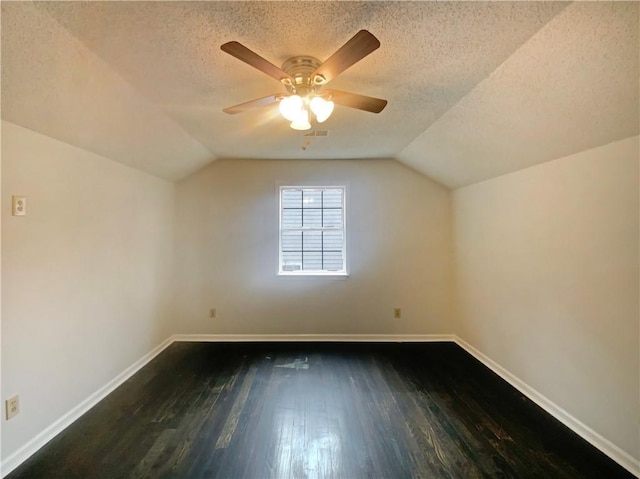 additional living space with dark hardwood / wood-style floors, vaulted ceiling, and a textured ceiling