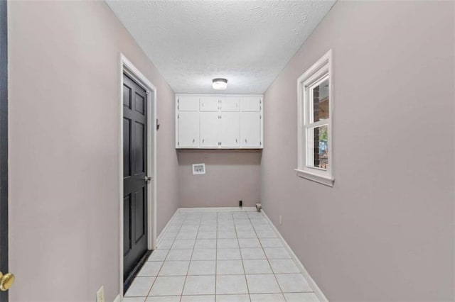 clothes washing area with cabinet space, light tile patterned floors, baseboards, hookup for a washing machine, and a textured ceiling