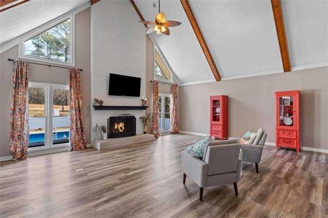 living room with a fireplace, baseboards, wood finished floors, and beamed ceiling