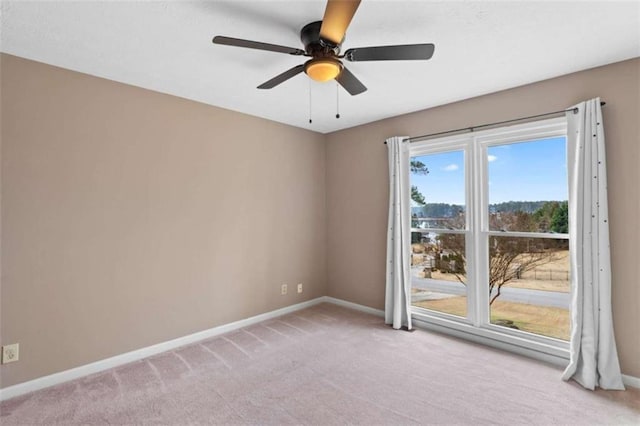 spare room featuring a ceiling fan, light carpet, and baseboards