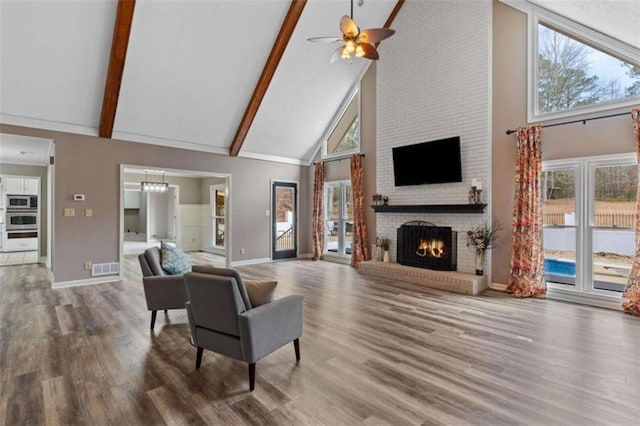 living area with high vaulted ceiling, a fireplace, and wood finished floors