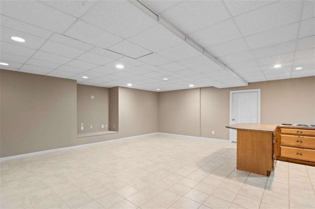 finished basement featuring a paneled ceiling, baseboards, and recessed lighting