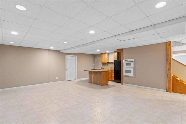 kitchen featuring double oven, a drop ceiling, open floor plan, freestanding refrigerator, and a center island