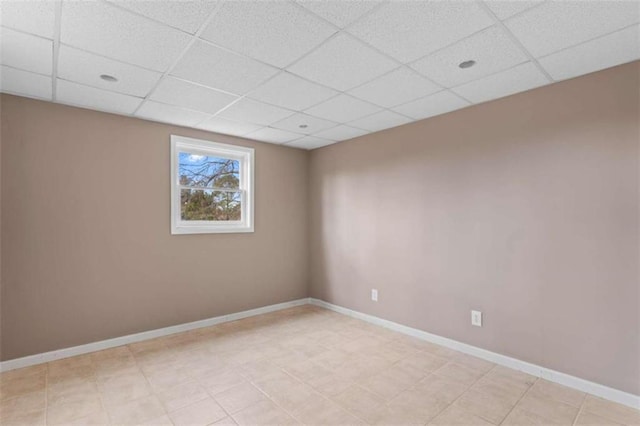 unfurnished room with a drop ceiling and baseboards