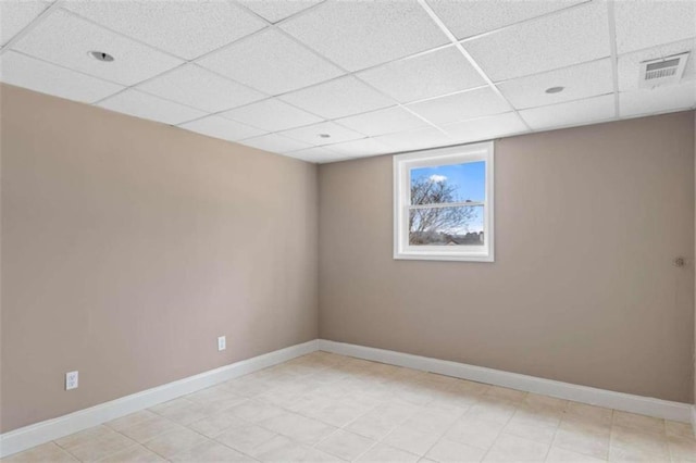 unfurnished room with a paneled ceiling, visible vents, and baseboards