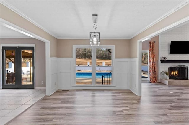 unfurnished dining area with ornamental molding, a fireplace, and wood finished floors