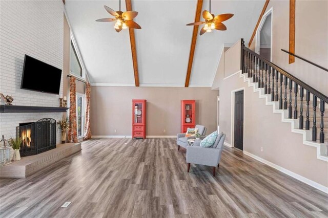 unfurnished living room featuring high vaulted ceiling, a brick fireplace, baseboards, and wood finished floors