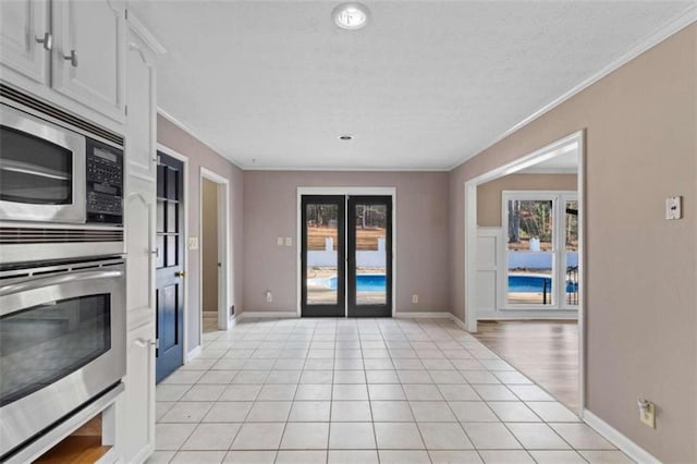 kitchen featuring light tile patterned floors, baseboards, ornamental molding, and stainless steel appliances