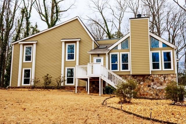 5035 Post Road Ct, Stone Mountain, GA 30088 - rear view of house featuring a chimney, stone siding, and stairs