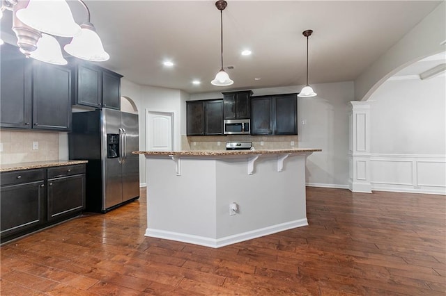 kitchen with a kitchen breakfast bar, decorative light fixtures, stainless steel appliances, and a center island