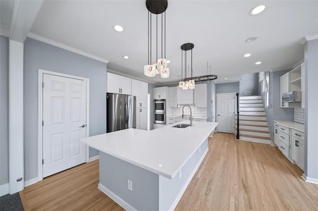 kitchen with sink, pendant lighting, stainless steel appliances, a large island, and white cabinets