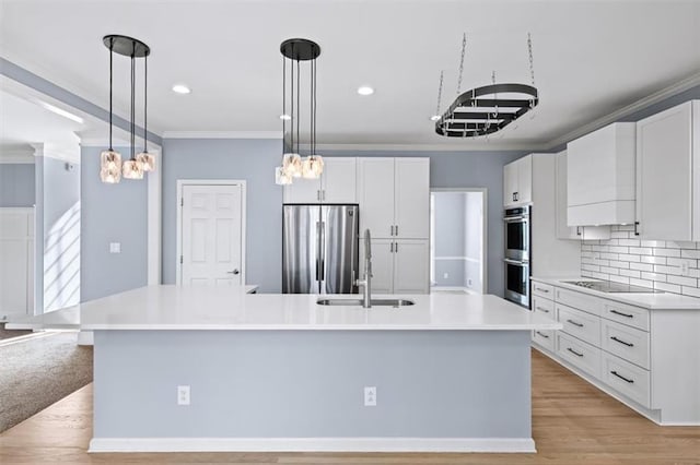 kitchen featuring crown molding, stainless steel appliances, an island with sink, and white cabinets