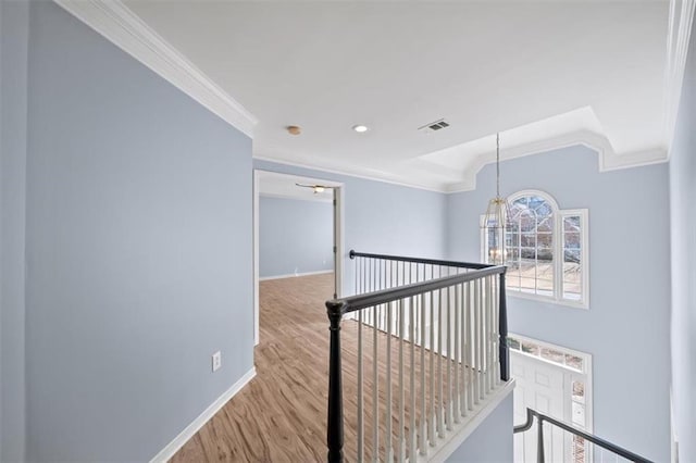 corridor featuring vaulted ceiling, ornamental molding, a chandelier, and light wood-type flooring