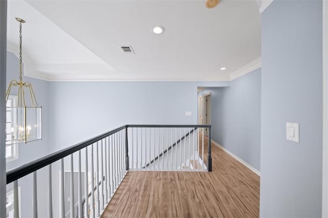 hallway with an inviting chandelier, ornamental molding, and hardwood / wood-style flooring