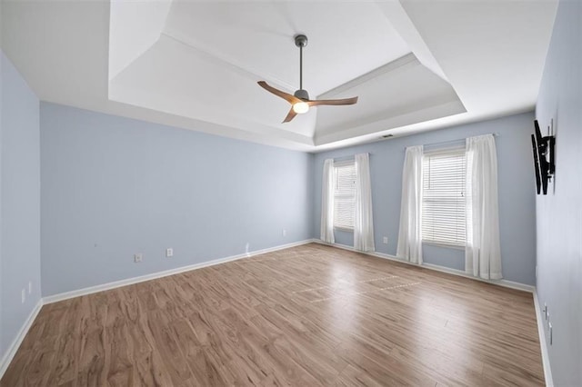 empty room featuring a tray ceiling, wood-type flooring, and ceiling fan