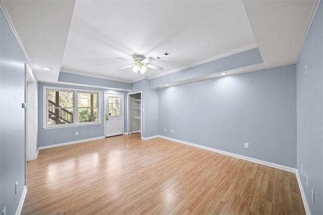 unfurnished room with crown molding, ceiling fan, a tray ceiling, and light wood-type flooring