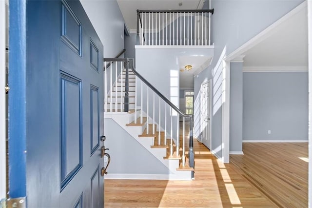 entrance foyer with ornamental molding, light hardwood / wood-style flooring, and a high ceiling