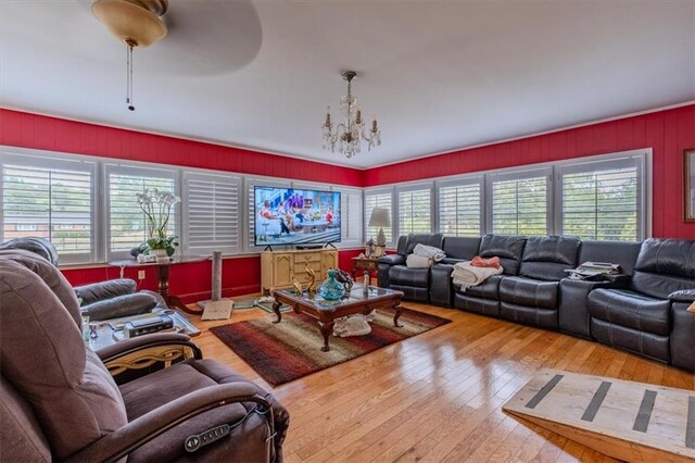 living room with ceiling fan with notable chandelier and hardwood / wood-style flooring