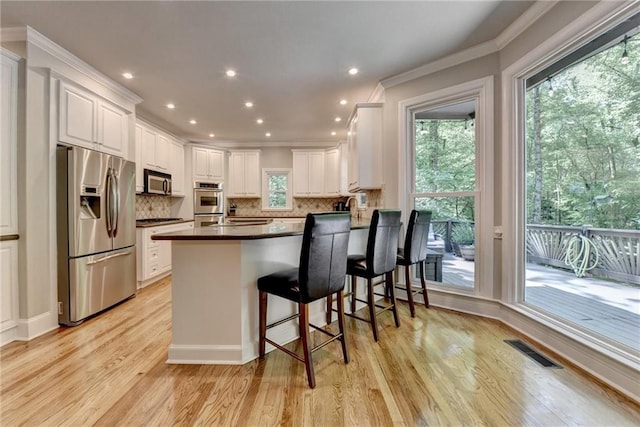 1595 Northcliff Trce, Roswell, GA 30076 - kitchen featuring appliances with stainless steel finishes, dark countertops, ornamental molding, a peninsula, and light wood-style floors