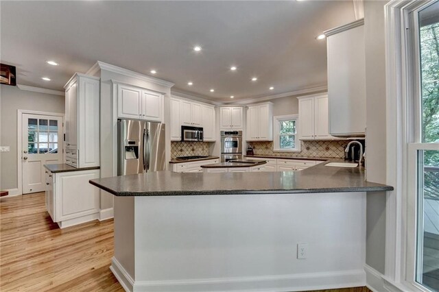 1595 Northcliff Trce, Roswell, GA 30076 - kitchen with appliances with stainless steel finishes, ornamental molding, dark countertops, decorative backsplash, and light wood-style floors