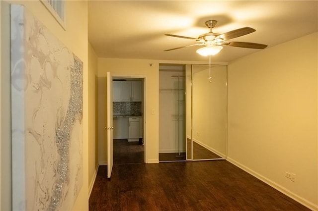 unfurnished bedroom with ceiling fan, dark hardwood / wood-style flooring, and a closet