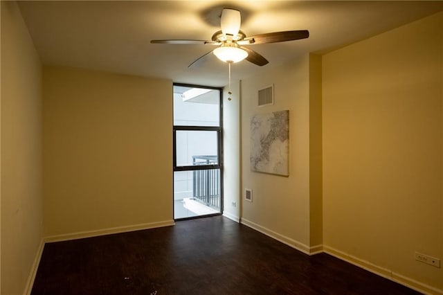 empty room featuring dark hardwood / wood-style flooring, expansive windows, and ceiling fan