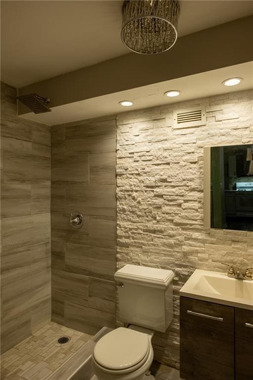 bathroom with tiled shower, vanity, and toilet