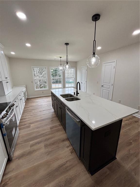 kitchen with pendant lighting, sink, white cabinets, a kitchen island with sink, and stainless steel appliances