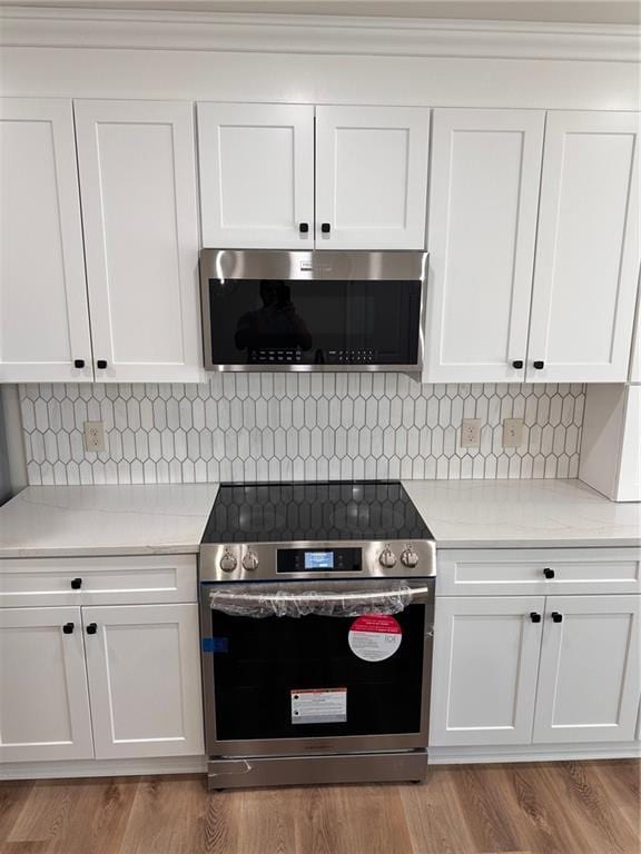 kitchen featuring light stone countertops, stainless steel appliances, and white cabinets